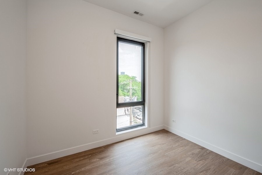 a bedroom with a large window and hardwood floors